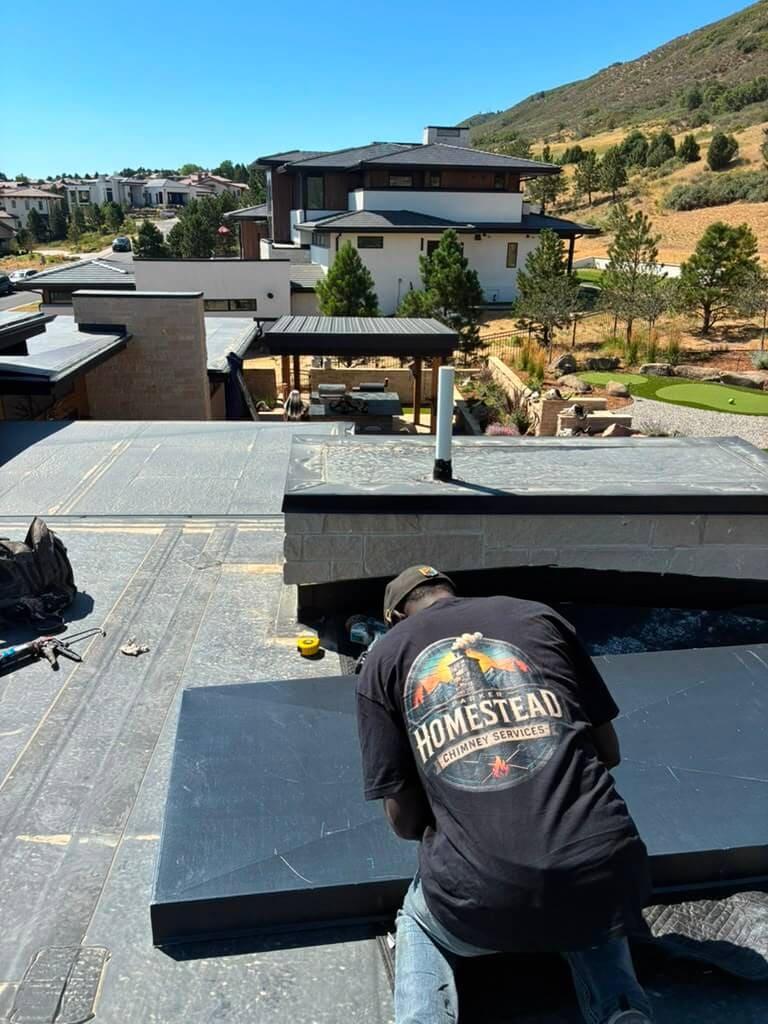 Installing a custom chase cover on a stone chimney above an outdoor living area in Colorado