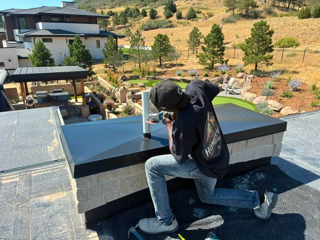 Sealing a flue pipe collar on a new black chase cover during a chimney cap installation