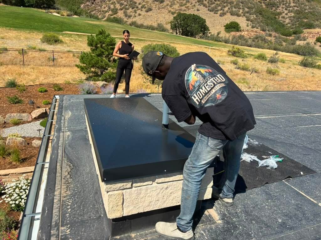 Parker Homestead Chimney technician installing a custom black chase cover on a stone chimney chase