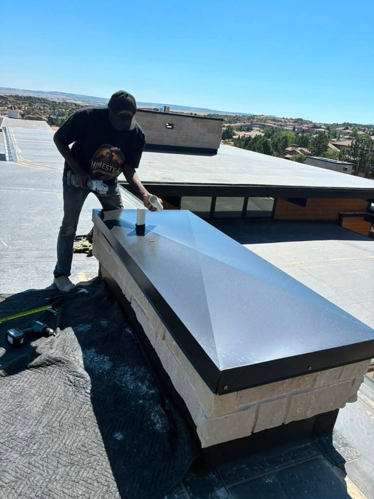Finished custom black chase cover with storm collar on a stone chimney chase in Colorado